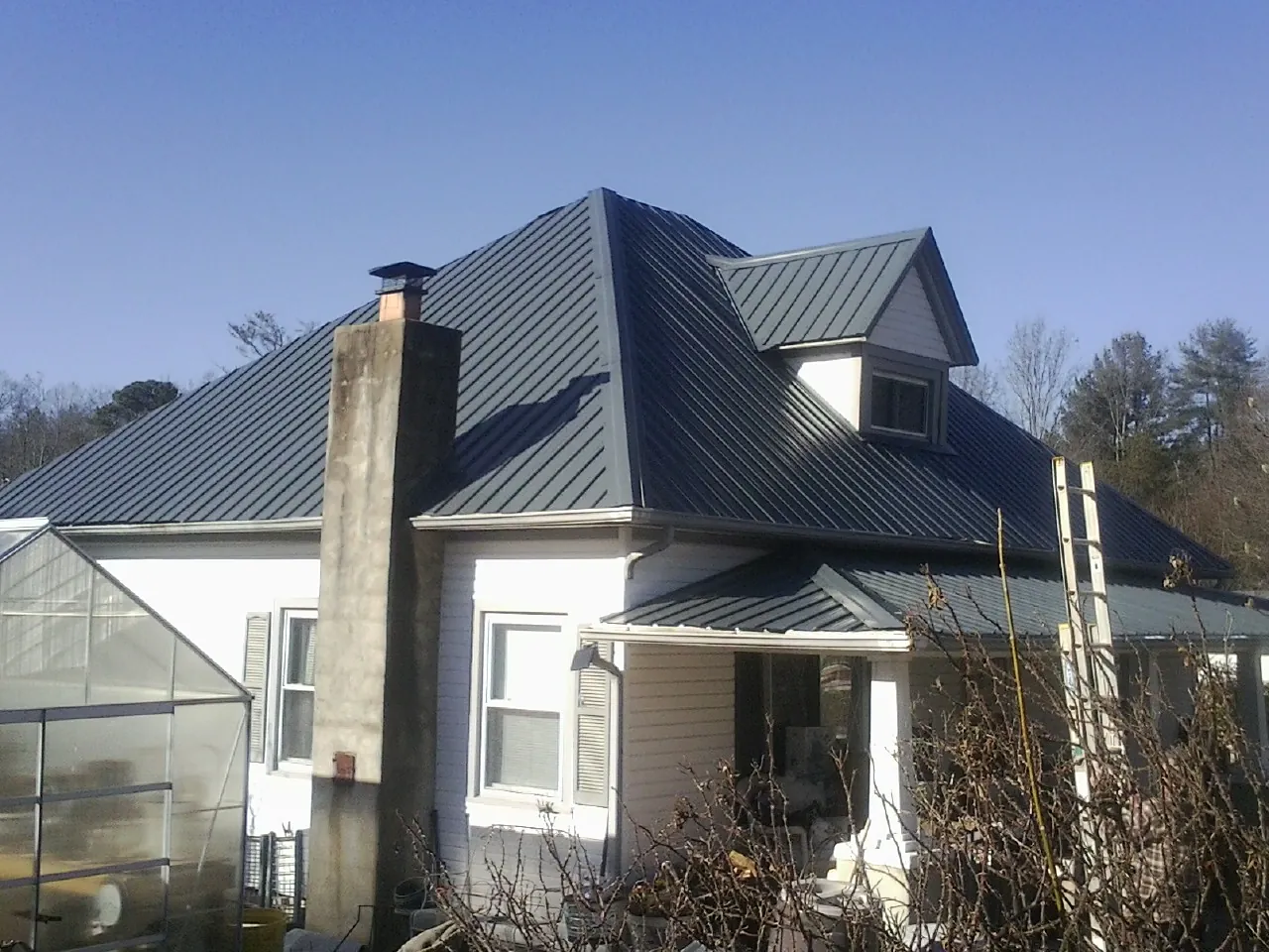 Dark blue standing seam metal roof on a white farmhouse with dormer — Slate & Tile Roof Repair by Roofing Brothers in Lagunitas