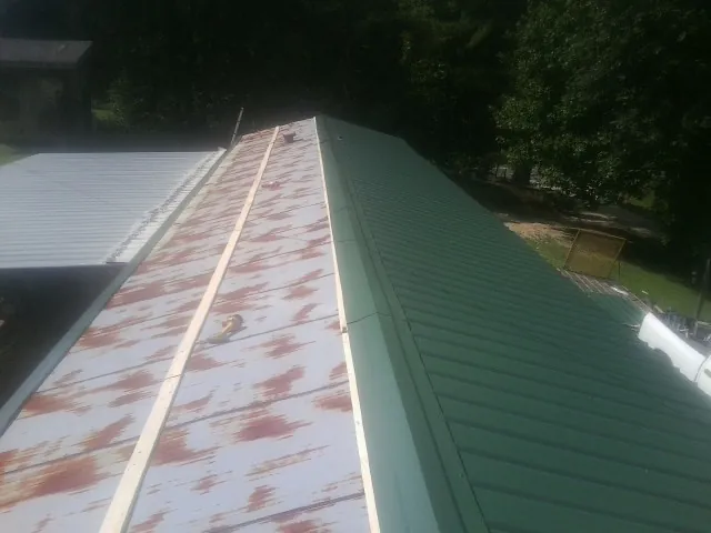 Old rusted panels beside newly installed green metal roofing — Wind Damage Roof Repair by Roofing Brothers in Lagunitas