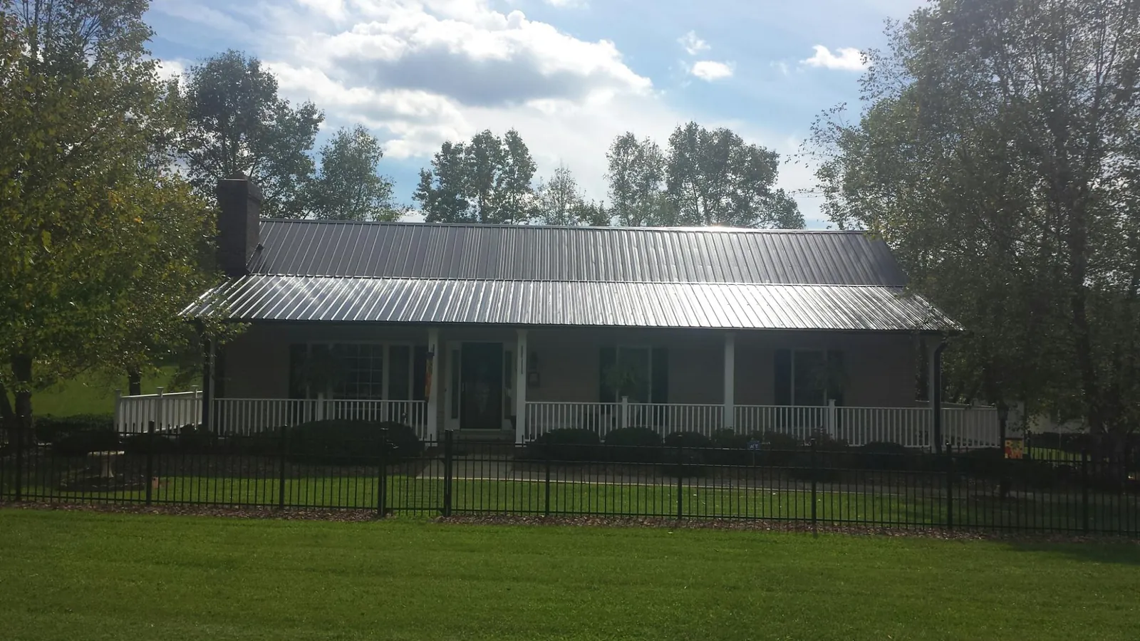 Gray metal roof on a brick ranch with a full width front porch — Gutter Guard Installation work by our crew in Lagunitas