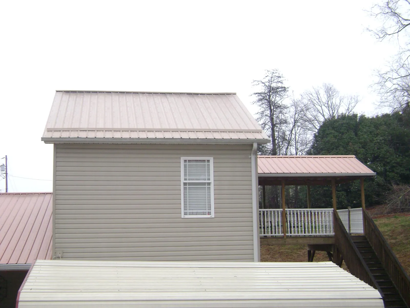 Tan metal roofs on a two story addition and attached porch, from a Roof Replacement job in Lagunitas